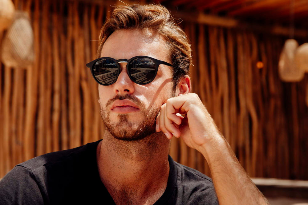 Modelo llevando las gafas de sol redondas para hombre Dorelion Nova negras con lentes polarizadas y protección UV400.